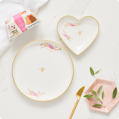 Elegant white and heart shaped plates on marble countertop with a can Fancy Feast Gems